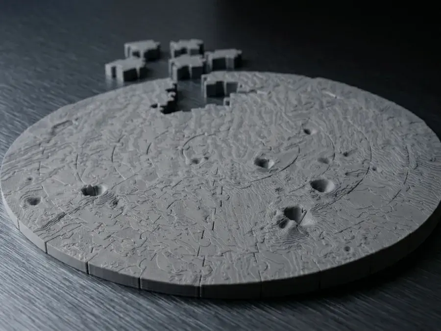A printed lunar puzzle of the Apollo 11 landing area on a dark table.