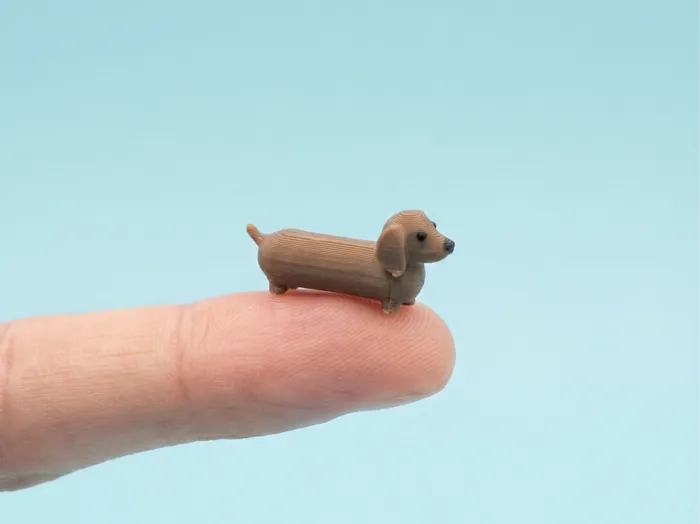 A tiny printed dachshund on a fingertip.